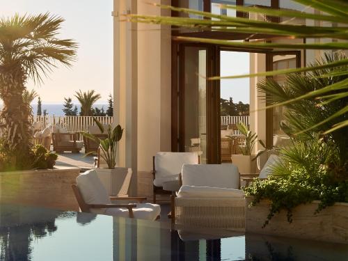 a lobby with chairs and a pool with a view at Grecotel LUXME Kos in Kos Town