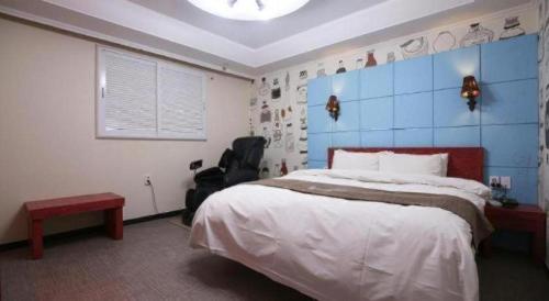 a bedroom with a large bed with a blue wall at Luxury Motel Daejeon in Daejeon