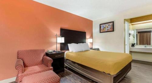 a hotel room with a bed and a chair at Econo Lodge Urbandale - Northwest Des Moines in Urbandale