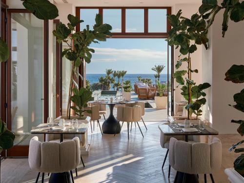 a restaurant with tables and chairs and a view of the ocean at Grecotel LUXME Kos in Kos Town