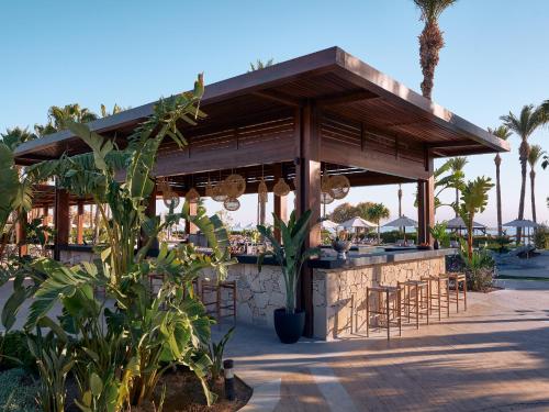a restaurant with a bar with chairs and palm trees at Grecotel LUXME Kos in Kos Town