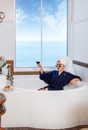 a woman sitting in a bath tub holding a wine glass at The IMPERIAL Vung Tau Hotel in Vung Tau