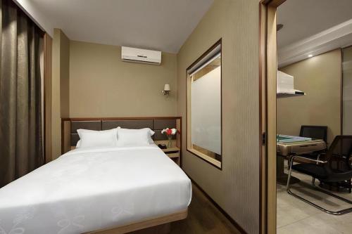 a bedroom with a bed and a desk and a chair at Hanyong Hotel Shenzhen International Exhibition Center in Shenzhen
