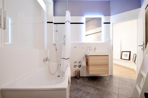 a white bathroom with a tub and a sink at Como Design-Apartment close to Isar river area - centrally located in Munich