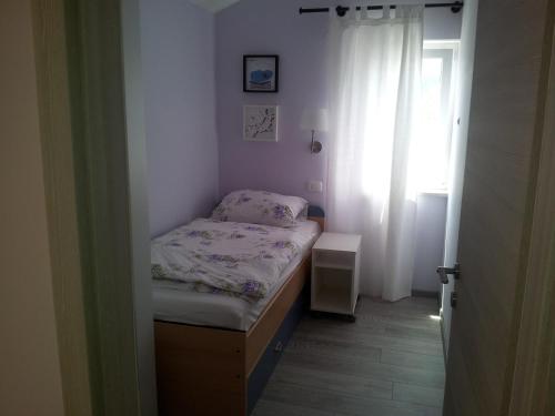 a small bed in a room with a window at Apartment Diminic Melin in Cres