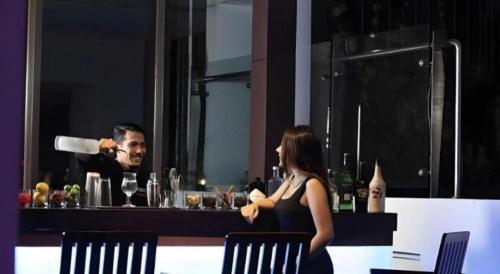 a man and a woman sitting at a bar with a bartender at Hotel Grandhika Pemuda in Semarang