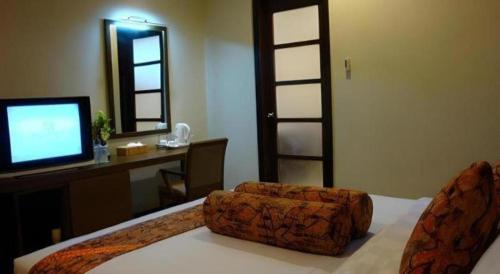 a bedroom with a bed with a television and a desk at The Luxio Hotel in Sorong