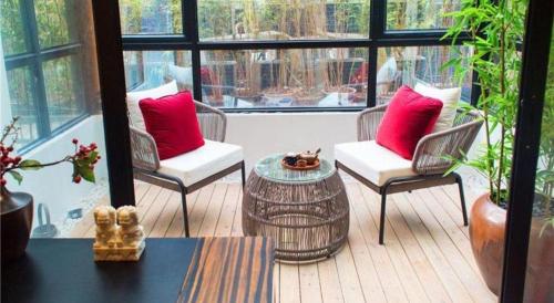 a porch with chairs and a table with red pillows at Yuan Culture Hotel Shenzhen World Shajing in Shenzhen