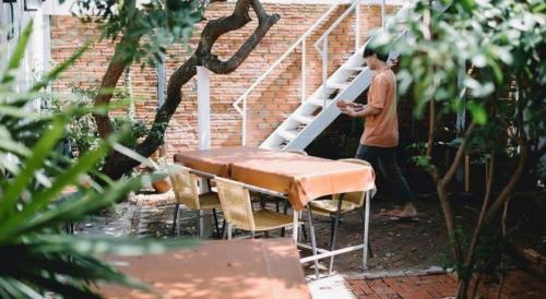 a man standing on a ladder next to a table at THE GOOSE HOUSE UBON in Ubon Ratchathani