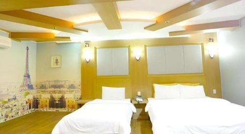 a bedroom with two beds and a mural of the eiffel tower at Hotel Head-One in Uijeongbu