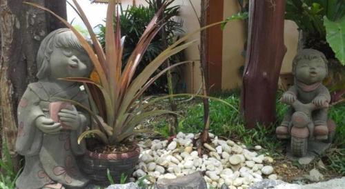 two statues of children in a garden with plants at Wanghin Bungalow in Surat Thani