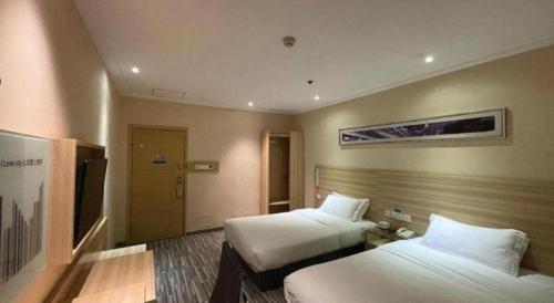 a hotel room with two beds and a door at City Comfort Inn Wuhan Wansongyuan Wangjiadun East Metro in Wuhan