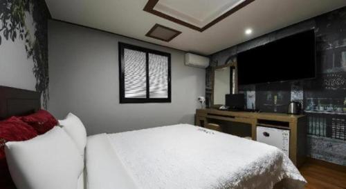 a bedroom with a white bed and a flat screen tv at Chuncheon World Hotel in Chuncheon