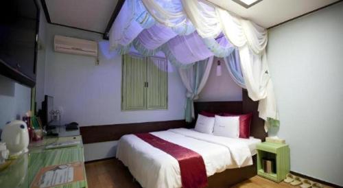 a bedroom with a bed with curtains above it at Chuncheon World Hotel in Chuncheon