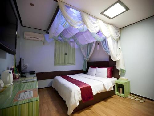 a bedroom with a large bed with a canopy at Chuncheon World Hotel in Chuncheon
