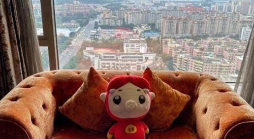 a stuffed animal sitting on a couch in front of a window at King Century Hotel in Zhongshan