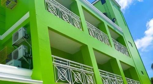 a green building with balconies on the side of it at Hotel Camila 2 in Dipolog