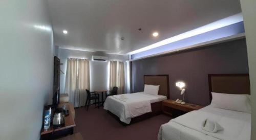 a hotel room with two beds and a table and chairs at Hotel Camila 2 in Dipolog