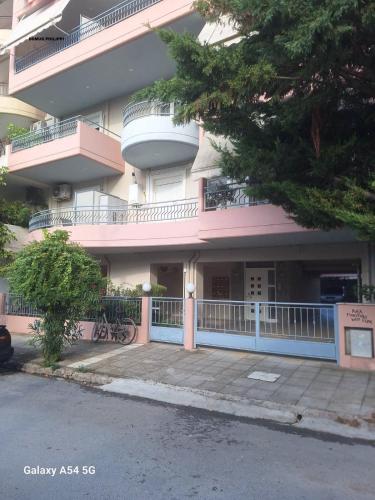 a pink building with a balcony and a parking lot at Domus Philippi in Larisa