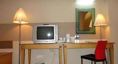 a room with a television on a desk with a red chair at Hotel Formosa in Manado
