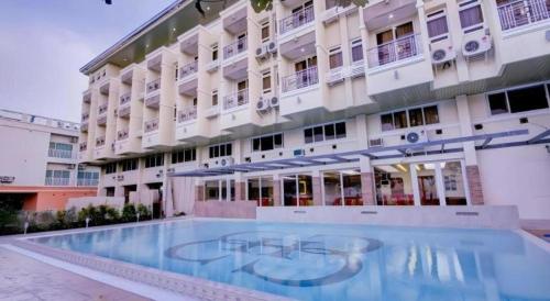 a hotel with a swimming pool in front of a building at Subic Grand Harbour Hotel Subic Bay in Olongapo