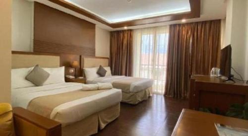 a hotel room with two beds and a window at Subic Grand Harbour Hotel Subic Bay in Olongapo