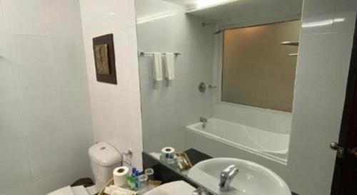 a white bathroom with a sink and a mirror at Subic Grand Harbour Hotel Subic Bay in Olongapo