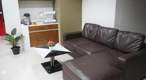 a living room with a brown leather couch and a table at Regent Room Hotel in Suratthani