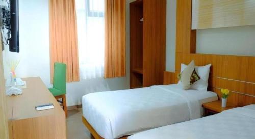a hotel room with two beds and a desk and a chair at Lotus Hotel Subang in Bandung