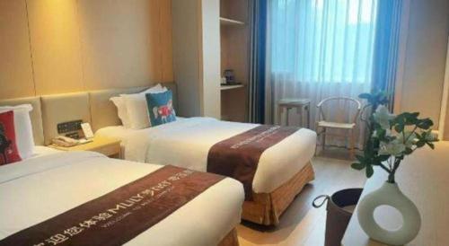 a hotel room with two beds and a vase with flowers at Beijing Inner Mongolia Hotel Chaoyang in Beijing