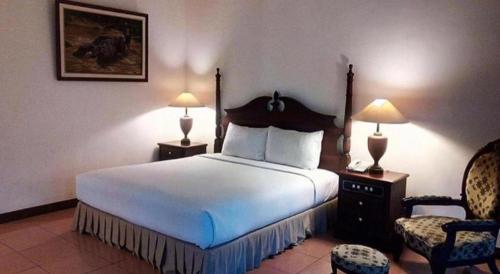 a hotel room with a large bed and a chair at The Oxalis Regency Hotel in Magelang