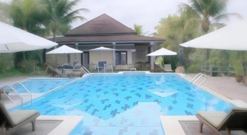 a large blue swimming pool with two chairs and umbrellas at The Oxalis Regency Hotel in Magelang