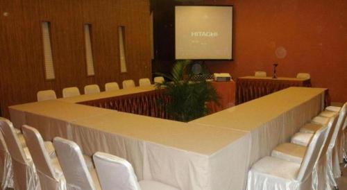 a large meeting room with white chairs and a screen at The Oxalis Regency Hotel in Magelang