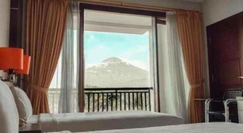 a bedroom with a view of a mountain through a window at The Oxalis Regency Hotel in Magelang
