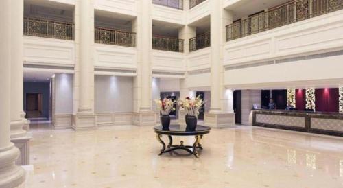 a large lobby with two vases with flowers on a table at Zaozhuang Hotel in Zaozhuang
