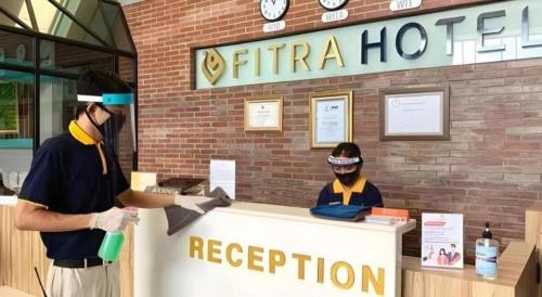 two people standing at a counter in front of a hotel at Fitra Hotel Majalengka in Majalengka