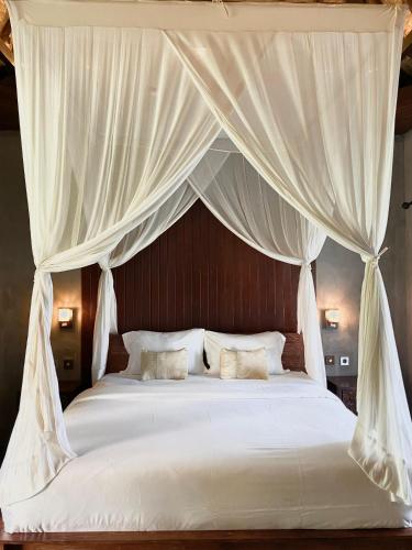 een slaapkamer met een hemelbed met witte lakens en kussens bij SoulStar in Ubud