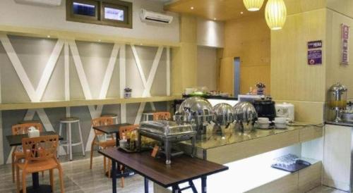 a kitchen with a counter and tables and chairs at Hotel D' CaLia Tarakan in Tarakan