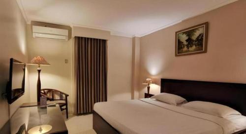 a hotel room with a bed and a glass table at Plaza Hotel Tegal in Tegal
