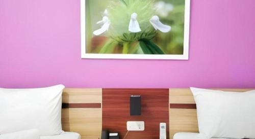 a bedroom with a pink wall and a picture above a bed at GARDEN HOTEL MAJALENGKA in Majalengka