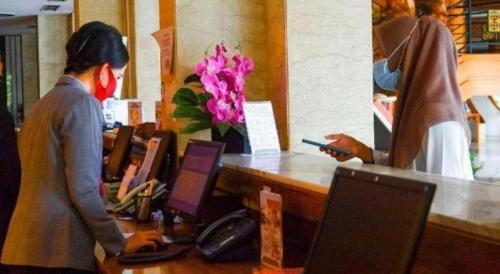 two people standing at a counter with their computers at Labersa Grand Hotel &Convention Center in Pekanbaru