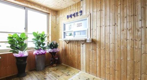 a room with a wooden wall with a tv and flowers at Dubai Motel in Daejeon