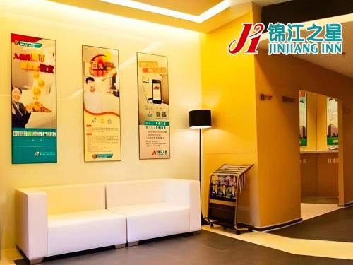 a living room with a white couch and posters at Jinjiang Inn Qingdao Development Zone Jinggangshan Rd. in Huangdao