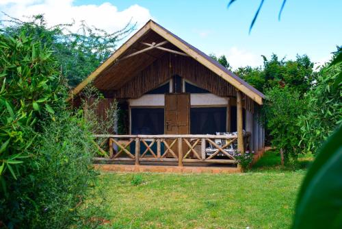 a small house with a wooden porch and a door at Boma Simba Safari Lodge in Voi