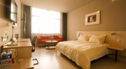 a bedroom with a bed and a chair and a window at Jinjiang Inn Qingdao Development Zone Jinggangshan Rd. in Huangdao