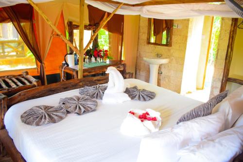 a bed in a room with towels on it at Boma Simba Safari Lodge in Voi