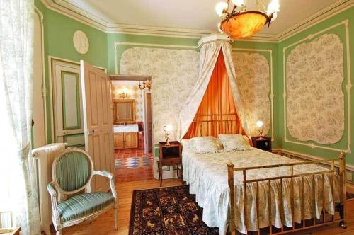 une chambre avec un grand lit et une chaise dans l'établissement Domaine de Gaudon, à Ceilloux
