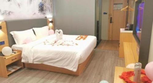 a bedroom with a bed with white sheets and decorations at Sheng Lin Na Hotel Minzhi Branch in Shenzhen