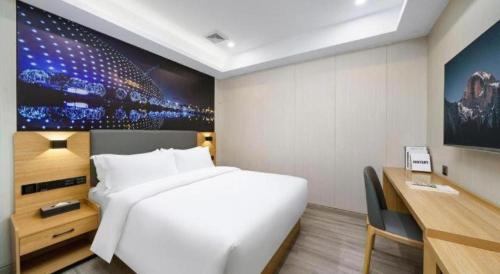 a bedroom with a large white bed and a desk at Sheng Lin Na Hotel Minzhi Branch in Shenzhen