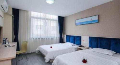 a hotel room with two beds and a window at 7 Days Inn Zhenjiang Jiangsu University in Zhenjiang